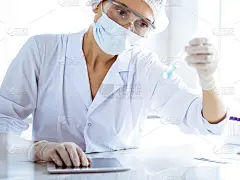 专业女科学家戴着防护眼镜，在实验室研究试管和试剂。医学和科学研究的概念