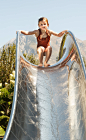 Young girl sat at the top of stainless steel water slide, with water jets cooling the slide.