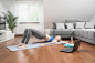 Young woman with laptop doing yoga on exercise mat in living room, Bavaria, Germany