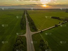 一架无人机在有十字路口的双车道公路上拍摄的美丽景色，日落时的绿色田野