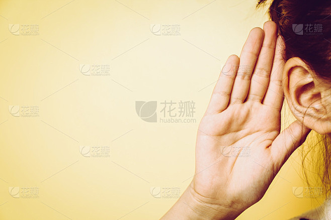 女孩把她的手靠近耳朵，在墙上仔细地听着