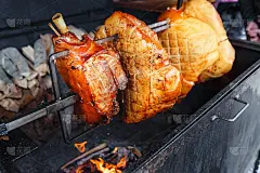一大块猪肉火腿肉在烤架上的明火上烤着。街头捷克食物