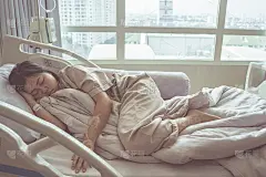 亚洲妇女生病的流感已承认医院与生理盐水静脉(iv)在线手压。病人在病人的床上休息。