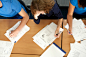 Royalty-free Image: Three students sitting at desk with worksheets overhead…