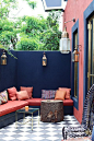 Closed in patio with deep blue painted walls paired with coral accents and cushions.