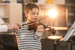 Little artistLittle happy 6-year-old boy learning to hold and play the violin