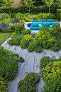 zwei blaue Sofas, ein grüner Garten mit bunten Blumen, Platten in grauer Farbe, moderne Gartengestaltung