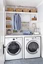 Fabulous laundry room with beadboard ceiling and gray slate tile floors. A side by side front loading Frigidaire washer and dryer pair with marble countertop and folding space. Built-in shelving flanks the window and holds seagrass baskets and laundry ess