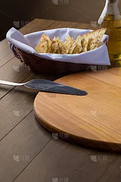 柠檬胡椒粉烤面包片装在一个小篮子里，木板和钢铲放在木桌上。典型的意大利食物，广泛用作披萨店的开胃菜。