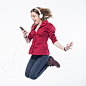 Cheerful Young Woman Jumping While Listening Music Against White Background