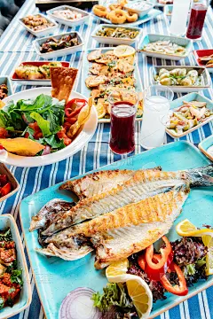 烤鱼、沙拉和蔬菜。海鲜，烤肉，meze, raki, ouzo，开胃菜和沙拉在希腊或土耳其鱼餐厅的桌