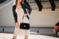 Fashion details close up of attractive woman walking in street in fashionable outfit, holding purse, wearing black leather jacket and white lace dress, spring autumn style