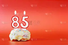 85岁生日。纸杯蛋糕，上面有燃烧着的白色蜡烛，数字是85。鲜艳的红色背景与复制空间