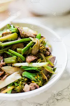 这张特写照片是一个白色的碗，上面放着中餐馆风格的牛肉和花椰菜。