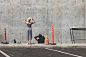 一位穿着裙子和帽子的女人站在靠近交通锥的混凝土墙旁边
