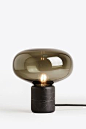 la lampe de table noire Karl-Johan réalisé par Digne Hytte, édition de New Works est fait en verre façon fumé et posé sur un support en marble noir
