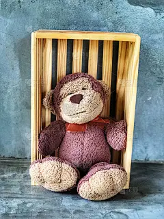 可爱的猴子微笑娃娃坐在水泥背景的木箱上。给你特别的一个惊喜礼物。复制空间和复古风格