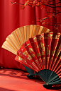 Golden fans and fans, red backdrop, and other decorations, in the style of vivid color blocks, fan ho, 3d, wrapped, neo-traditionalist, imitated material, trompe-l'oeil folds