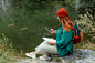 时髦的女人与绿色背包手持智能手机和纸质地图户外。全身照片。徒步旅行活跃的女性生活方式坐在岩石上。戴着红帽子的女孩在自然湖背景下放松。照片摄影图片