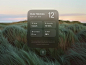 This may contain: an iphone screen showing the weather and time in front of a grassy field at sunset