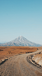 beautiful-vertical-shot-narrow-curvy-muddy-road-with-high-mountain