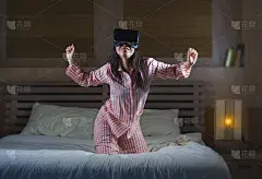 年轻快乐和兴奋的女人玩虚拟现实VR眼镜耳机设备有乐趣在床上有3D体验视频游戏震惊的看和触摸数字幻觉