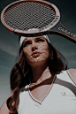 This may contain: a woman holding a tennis racket over her head