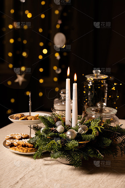 圣诞装饰:亚麻桌布上放着两支白色蜡烛和传...