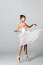 优雅的非裔美国芭蕾舞女演员在白色背景上穿着裙子跳舞