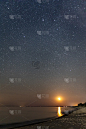 夜晚的星空和上升的月亮在海滩上