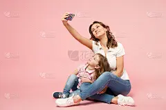 穿着浅色衣服的女人和可爱的孩子宝贝女孩玩得很开心。母亲，小女儿被隔离在淡粉色的墙壁背景上，画室肖像画