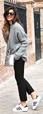 Natalia Cabezas is wearing a grey knit sweater and black trousers from Zara, sneakers from Adidas, sunglasses from Prada and the bag is from Guess: 