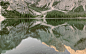 Granite mountains reflected in the still surface of Lake Pragser Wildsee