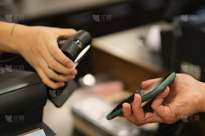 近距离拿着手机扫描支付在咖啡店。软焦点