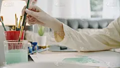 亚洲少女手绘和绘画她的艺术在客厅。她用笔记本电脑和朋友视频通话，同时用水彩和画笔在白纸上创作艺术项目