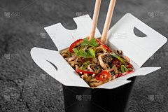 炒锅内装麻辣面条，装在黑色食物容器中。快餐外卖服务。中餐的外卖。