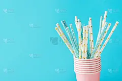 白色和蓝色的纸饮料吸管与金星圆点图案在堆叠的粉红色杯子。零浪费自然友好的生物降解材料。生日派对节日庆
