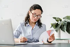 严肃的中年白人女商人在家里的办公室用笔记本电脑工作，检查文件，商业图表和在线图表。远程工作，自由职业