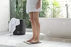 女人在浴室里站在数字体重秤上，节食的概念。