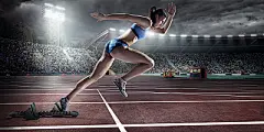 Female athlete sprintingProfessional female athlete sprinting from blocks on numbered start line on outdoor athletics track on . stadium full of spectators under a dramatic evening sky. Sprinter is wearing generic athletics kit.