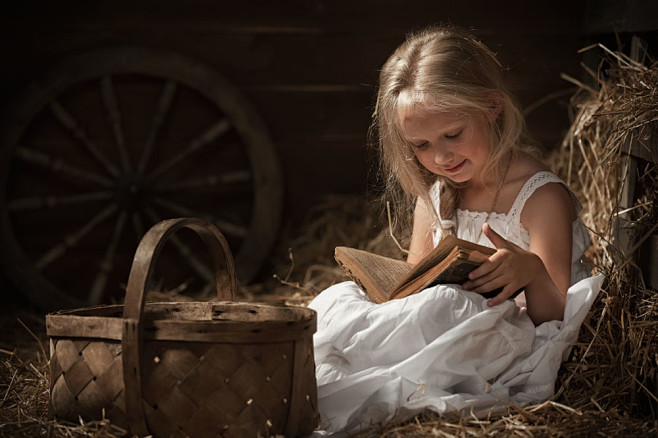 坐在草堆看书的可爱女孩图片