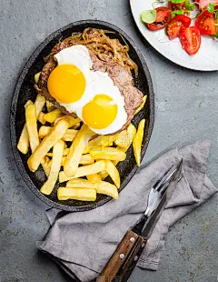 秘鲁的拉丁美洲食物。我是个笨蛋。牛肉，薯条，薯条和鸡蛋。配上沙拉。俯视图