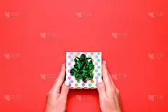女子呈现礼物与绿色缎带上郁郁葱葱的熔岩色背景，copyspace。情人节或母亲节贺卡时髦的颜色，俯视