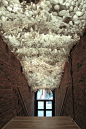 Alicia Basinger recently installed Replicas, a light installation that utilizes the entire ceiling space of the Kirkland Art Center’s main staircase entrance. This structure consists of thousands of white cylinders of various sizes dipped into acrylic and