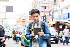 亚洲背包客在泰国考山路旅行时使用平板电脑