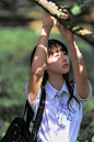 girl in white and blue polo shirt holding on brown wooden bar during daytime