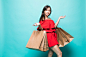 Happy shopping woman of asian holding bags, isolated on green wall. Free Photo