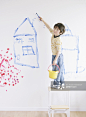 Canadian boy drawing picture on wall in room_创意图片