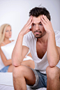 Young man sitting on the bed, against his angry wife. | Premium Photo