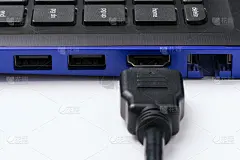 白色背景下的现代蓝色笔记本的HDMI接口附近的HDMI线